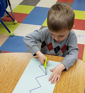 Boy cutting with scissors